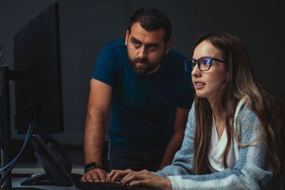 Cybersecurity student looking at computer screen with teacher