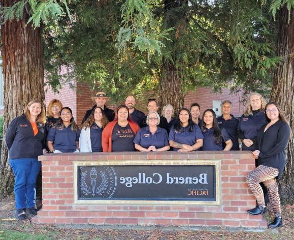 The staff of Benerd College standing behind the Benerd sign